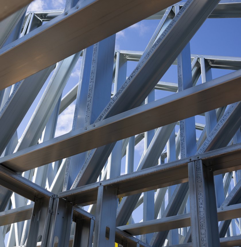 Looking up through a cold-formed steel frame, joists and trusses against the sky