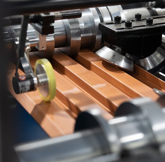 Roll-former rollers shaping woodgrain-printed steel cladding