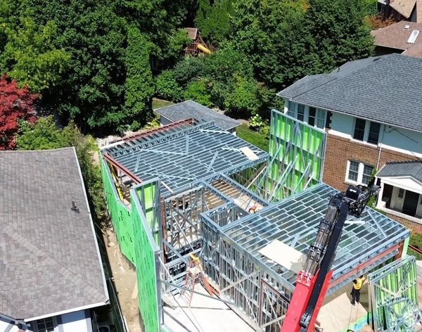 Drone view of the North York project: two-storey cold-formed steel frame with green sheathing and a crane
