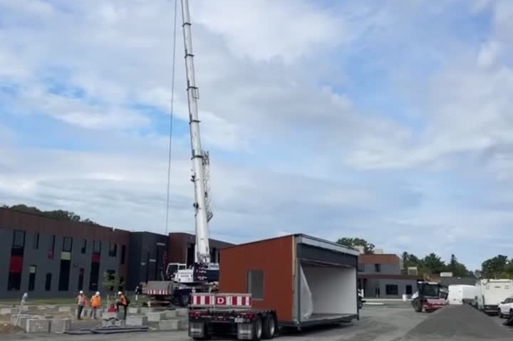 Orange modular classroom unit on a trailer in the plant yard
