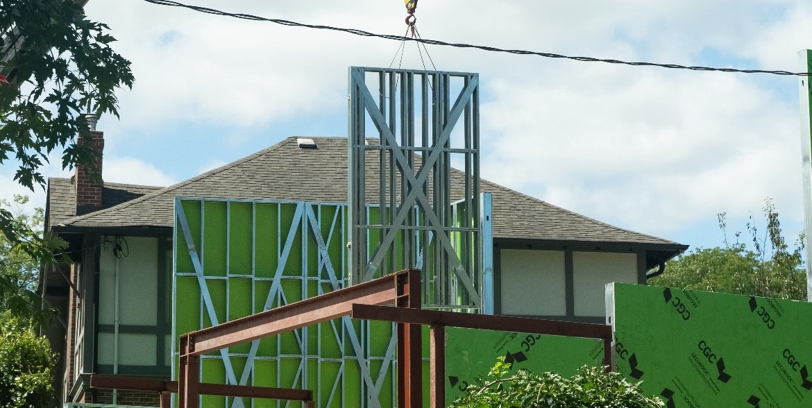 Crane lowering a cold-formed steel wall panel onto a residential addition